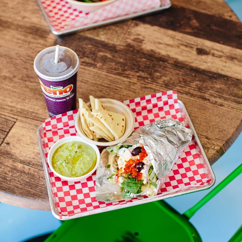 Peno Mediterranean Grill wrap, pita, hummus, and drink on a red checkered tray.