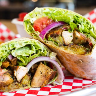 Caribbean Chicken Wrap. (Chicken, Plantains, Jalapeno Cilantro Hummus, Lettuce, Tomato, Onion, Cilantro Tahini Sauce)